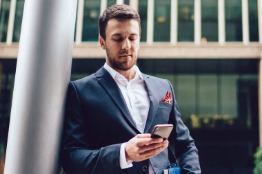 Resmi olarak akıllı erkek girişimci, finans bölgesinde şehir merkezinde ayakta duran cep telefonu aygıtı, iş hayatı ve iletişim konsepti ile posta denetimi yapıyor.