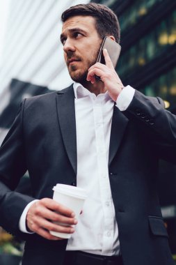 Kahveli ciddi bir adam, analitik uzmanını arıyor. İşletme ilerlemesi hakkında finansal bilgileri kontrol etmek için. Kafkas tüccarı hücresel aygıtla önemli bir gezinti konuşması yapıyor.
