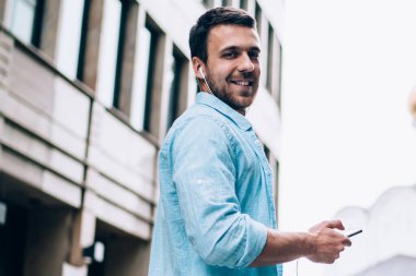 Kulaklıklı mutlu bir adamın yarım boy portresi. Mobil müzik listesinden elektro müzik dinleyerek zaman geçiriyor. Boş günlerinde cep telefonu kullanan beyaz bir erkek melodi sanatçısı.