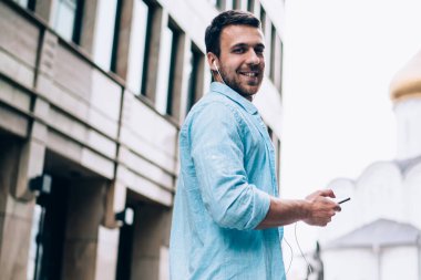 Kulaklıklı mutlu bir adamın yarım boy portresi. Mobil müzik listesinden elektro müzik dinleyerek zaman geçiriyor. Boş günlerinde cep telefonu kullanan beyaz bir erkek melodi sanatçısı.