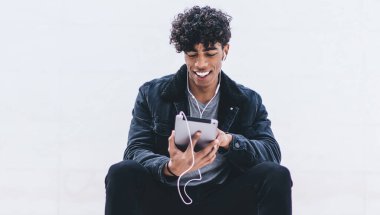 Neşeli milenyum hipster 'ı tanıtım geçmişi olan şehir merdivenlerinde dinleniyor ve favori müzik podcast' inin ses kitaplarıyla uygulama yüklemek için boş zaman harcamasını dinliyor.