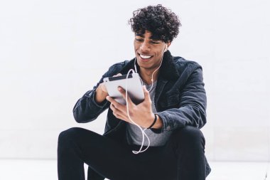 Gülümseyen erkek blogcu internet sitelerinde kulaklıkla komik filmler seyrediyor. Dokunmatik ped üzerinden hipster adam reklam için fotokopi duvarının yanında müzik listesi dinleyerek zaman geçiriyor.