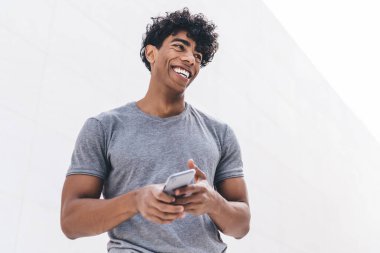 Elinde modern cep telefonu cihazı olan neşeli hippi adamın elinde komik bir e-posta mesajıyla gülüyor. Dijital cihazlı bir adam şehir ortamında gülümsüyor.