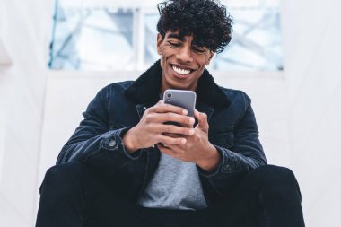 Gülümseyen, modaya uygun giyinmiş hippi adam, akıllı telefon ve hızlı internet bağlantısı kullanarak yabancı ülkeleri ziyaret etmeyi planlayan uçak şirketinin internet sitesinden bilet alıyor.