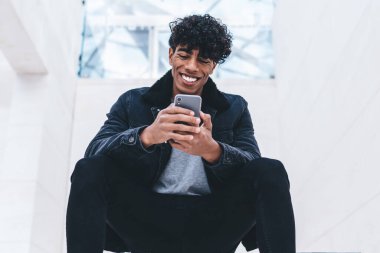 Gülümseyen, modaya uygun giyinmiş hippi adam, akıllı telefon ve hızlı internet bağlantısı kullanarak yabancı ülkeleri ziyaret etmeyi planlayan uçak şirketinin internet sitesinden bilet alıyor.