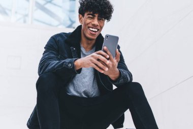 Latin hippi çocuk, sosyal ağda kendi web günlüğü için iyi yorumlar ve eleştiriler almaktan mutlu olan, cep telefonu kameraya gülümseyen neşeli genç adam.