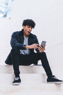 Moda kıyafetli hippi adam, cep telefonu uyarısı ile ilgili hayret verici bir mesaj aldı. Cep telefonu faturası için cep telefonu uygulaması kullanıyor.