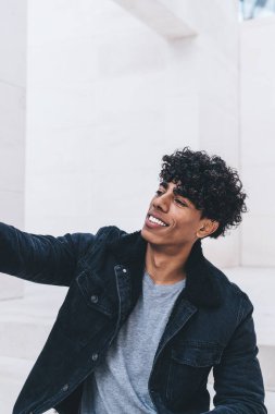 Hücresel cihazda fotoğraf çekerken gülümseyen hippi adam grup sohbetinde sanal arkadaşlara poz veriyor. Neşeli adam ön kamerayla boş zamanlarında fotoğraf çekiyor.