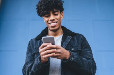 Günlük şık kıyafetler giymiş mutlu bir adam telefon ve sosyal siteye medya dosyaları paylaşmak için ağ kurmaktan keyif alıyor, milenyum erkek blogcu cep telefonu içeriği web sayfasından komik haberler okuyor