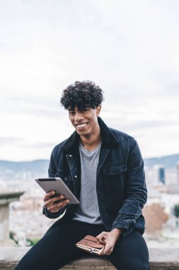 İspanyol başkentinin tarihi merkezinde modaya uygun giyinmiş mutlu erkek turistin portresi ve seyahat web günlüğündeki takipçilerle çevrimiçi sohbet sırasında kameraya gülümsüyor