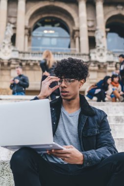 Barcelona 'daki Montjuic binası yakınlarında çalışan Latin erkek dijital göçebe bir sonraki seyahat için internet sitelerinde ucuz uçuş biletleri arıyor, gözlüklü yetenekli adam.