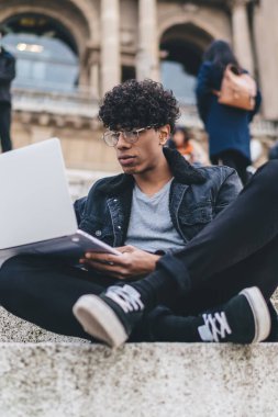 Klasik optik gözlüklü, düşünceli hippi adam gezintiden sonra Barcelona rehber bilgisi okuyan, uzaktan çalışan erkek dijital göçebe.