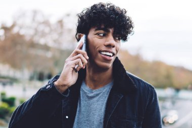 Mutlu Latin erkek turist, internet üzerinden iletişim kurmak için cep telefonu başvurusu yapıyor. Neşeli, modaya uygun giyinmiş hipster, uluslararası gezgin bağlantısıyla telefon ediyor.