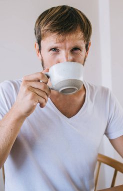 Kafeteryada boş zamanlarında aromalı kafein içen ve harika zevklerin tadını çıkaran yakışıklı hippi portresi, elinde sıcak çay ve poz veren beyaz erkek serbest oyuncu.