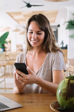 Elinde cep telefonu cihazı olan, sosyal ağlarda içerik blogunda komik metin yayınları okuyan, Endonezya internetini taramak için kullanan neşeli kadın serbest yazar.