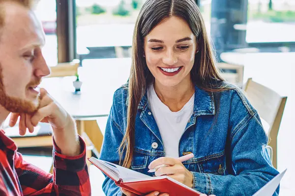 İnternette kendi web sayfası için ilginç içerikler oluşturma konusunda işbirliği yapan olumlu erkek ve kadın blogcular, gülümseyen kadın haberleri okurken not defterine bilgileri kaydediyor