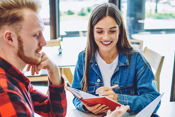 İnternette kendi web sayfası için ilginç içerikler oluşturma konusunda işbirliği yapan olumlu erkek ve kadın blogcular, gülümseyen kadın haberleri okurken not defterine bilgileri kaydediyor