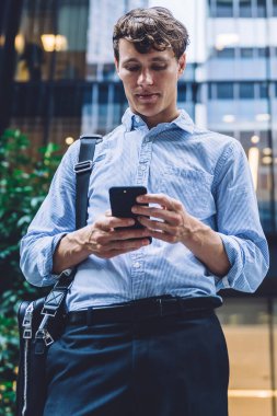 Açık havada cep telefonu kullanarak modaya uygun kıyafetler giyen resmi erkek yönetici, beyaz iş adamı online sohbet için 4G internete bağlı akıllı telefondan mesaj gönderiyor.