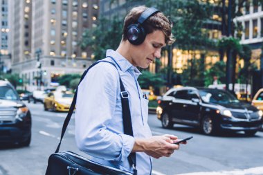 Modern cep telefonu cihazıyla ses mesajlarını kontrol eden zeki bir adamın yan görüntüsü gürültü önleyici kulaklıklar, web sitesinde evrak çantası arama metniyle beyaz erkek çalışan