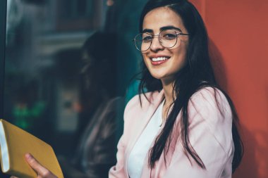 Neşeli İspanyol erasmus öğrencilerinin portresi kahveyle dinleniyor eğitim kitapçığıyla planlama sürecinin peşinden gitmek için dışarıda kameraya gülümseyen bilgi notları olan pozitif kadın.