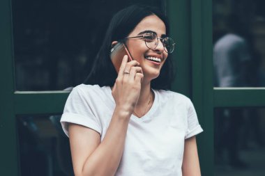 Fotokopi alanı tişörtlü heyecanlı hipster programcı arkadaşça akıllı telefon görüşmeleri sırasında gülüyor. Uzak iş sırasında ilginç bir web sitesi yaratmak için başlangıç grafik projesi ile iyi haberlerin tadını çıkarıyor.