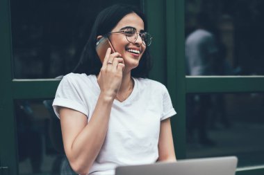 Fotokopi alanı tişörtlü heyecanlı hipster programcı arkadaşça akıllı telefon görüşmeleri sırasında gülüyor. Uzak iş sırasında ilginç bir web sitesi yaratmak için başlangıç grafik projesi ile iyi haberlerin tadını çıkarıyor.