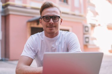 Çevrimiçi programlamaya ara verildiğinde kameraya bakan ve veri sistemini başlatan yetenekli erkek bilişim uzmanının portresi, başarılı bir adamın makale yaratmak için zaman harcaması