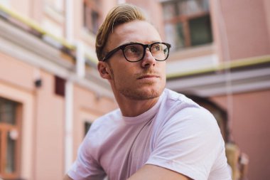 Dijital tabletli düşünceli hippi adam. Düşünceli bakışlar atıyor ve modern teknolojinin yaşam tarzı üzerindeki etkisini düşünüyor. Klasik gözlüklü ciddi bir erkek blogcu.