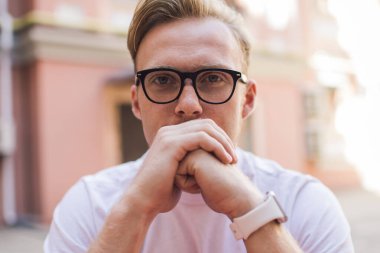 Görsel düzeltme için optik gözlüklü yakışıklı hippi portresi. Boş zamanlarında kameraya bakıyor. Klasik gözlüklü ciddi bir adam şehir merkezinde oturuyor.