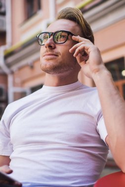 Görme düzeltmesi için optik gözlüklü hippi adam sosyal ağ için içerik metni üzerinde düşünüyor fikirleri online web sitesine paylaşmak istiyor, cep telefonu cihazlı düşünceli adam dışarıda