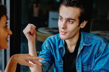 Yakışıklı genç adam, sevgilisiyle favori kitabı tartışıyor kafenin içinde akıllı telefonuyla kahve masasında oturuyor. İki öğrenci ortak proje hakkında birbirleriyle iletişim kuruyor.