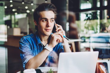 Akıllı telefondan konuşan sıradan giyinmiş hippi bilgisayarla iş yerinde oturup önemli bilgileri tartışıyor. Genç adam danışmanlık için müşteri hizmetlerini arıyor.