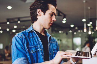 Ciddi erkek programcı testleri, tanıtım alanındaki uzak iş sırasında dizüstü bilgisayarda uygulama oluşturdu. Yetenekli hipster adam, Wi-Fi ile bağlantılı modern netbook 'taki belge dosyalarını araştırıyor.