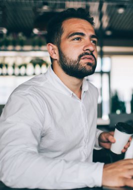 Bankacılık sistemiyle ilgili program kodları üzerinde düşünen düşünceli erkek bilişim uzmanı, resmi tişörtlü dalgın adam yazılım geliştirme projesi hakkında düşünüyor.