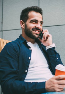 Başarılı sakallı serbest çalışan internetteki internet programının kahve molası sırasında iletişim kurmak için arkadaşına telefon ediyor. Pozitif hipster adam cep telefonuyla arıyor ve dışarıda geziniyor.