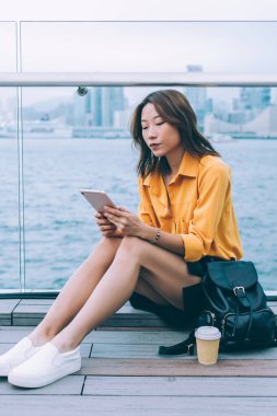 Çekici bin yıllık nesil, Hong Kong 'da nehir kenarında dinlenirken Çin teknolojisi kullanmakla ilgili içerik metni yazıyor ve modern dokunmatik kağıt üzerinde yazıyor, güzel bayan öğrenci medyayı arıyor.