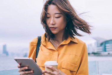 Güzel Japon hipster öğrenci kontrol şehir ortamında duran modern dokunmatik ped tebligat aldı ve kurulum için kamusal internet bağlantısı kullanarak, milenyum kadın test uygulaması