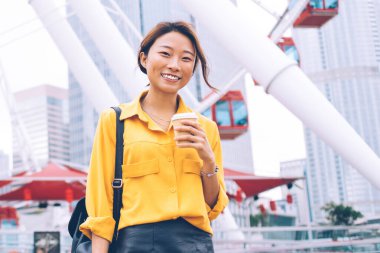 Arka planda park eğlencesi olan Hong Kong şehir merkezinde poz veren, şık giyinmiş neşeli kadın portresi, Çin tatillerinde eğlenen pozitif kadın turist.