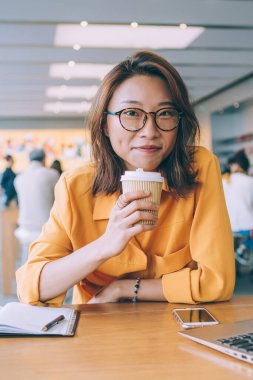 Klasik bardaklı çekici kız öğrencilerin portresi. Öğrenme ve ders çalışmalarına ara verildiğinde ellerinde kahve ile kameraya bakıyorlar. Serbest çalışmak için güzel bir kadın günü geçiriyor.