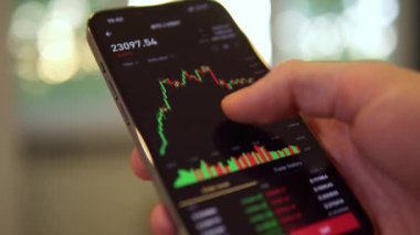 Businessman scrolling on his phone chart of BTC cryptocurrency value. Bitcoin value chart