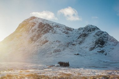 Karla kaplı Buachaille Etive Mor 'a karşı Lagangarbh Hut, İskoçya' nın Glencoe şehrinde ikonik bir dağ. 