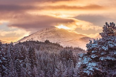 The snow-capped peak of Stob a' Choire Mheadhoin, a Munro mountain in the Scottish Highlands, at sunset. As seen from Laggan Dam clipart