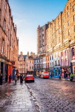 Edinburgh, İskoçya - 22 Ocak 2024: Edinburgh 'daki Victoria Caddesi boyunca uzanan renkli mağazaların ve eski mimarinin güneşli manzarası 