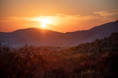 The sun rises over the hills at Pilanesberg National Park, situated in an ancient volcanic crater in South Africa clipart