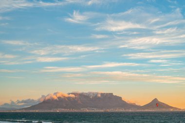 Güney Afrika 'nın Cape Town kentindeki Bloubergstrand' da güneşli bir günde okyanusun üzerindeki masa dağı.