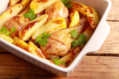 Roast chicken drumsticks with wedges of potatoes