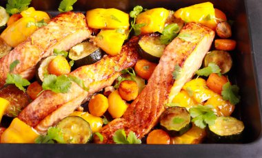 Roast salmon with vegetables on baking tray