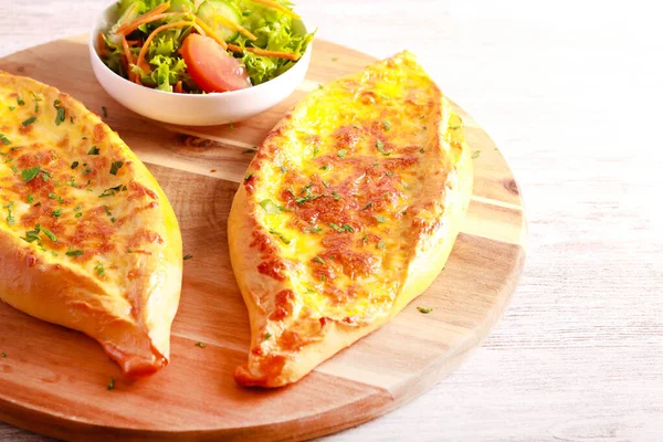 Cheese boat, crusty bread with melted cheese on wooden board