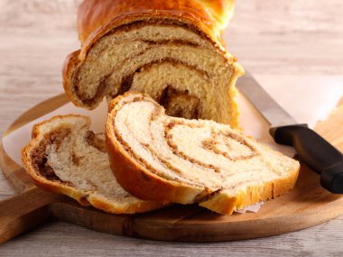 Ceviz ve hurma dolu, ahşap bir tahtanın üzerinde dilimlenmiş tatlı girdap ekmeği.