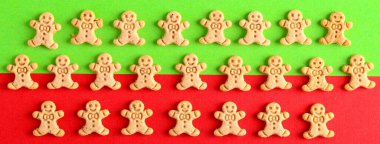 Mini zencefilli adam kurabiyeleri yeşil ve kırmızı arka planda. Yeşil ve kırmızı üzerine Noel sembolleri deseni